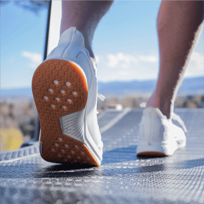 Person walking on treadmill outside in white shoes with gum sole #color_white-gum-rn
