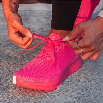 Person tying neon pink running shoe laces #color_neon-pink-rn