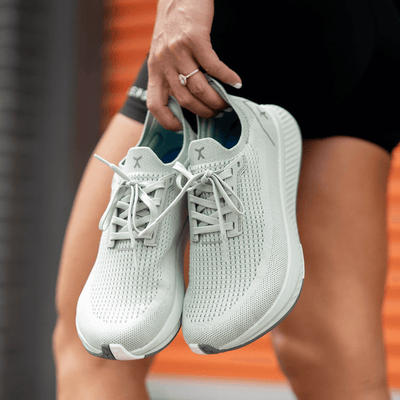 Woman carrying running shoes #color_calcite-green-rn